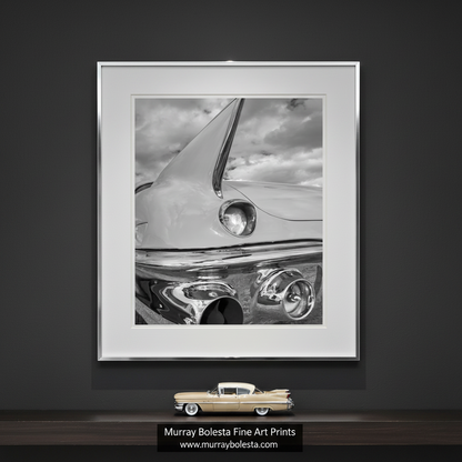 A close-up black and white photograph of the front end of a classic car, focusing on the chrome bumper and headlights. Black and White Cadillac Photo Art Print with Tail Fins by Murray Bolesta