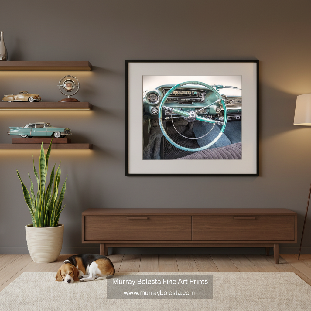 Cadillac art by Murray Bolesta! A framed art print of a vintage car dashboard and steering wheel in teal and black, displayed on a dark gray wall in a modern living room mockup with a wooden console, shelves, and a sleeping dog.