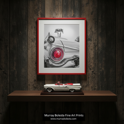 A black and white photograph of a classic car with a red tail light, featuring palm trees in the background. Ford Fairlane Photography Art Print as Automotive Wall Decor by Murray Bolesta