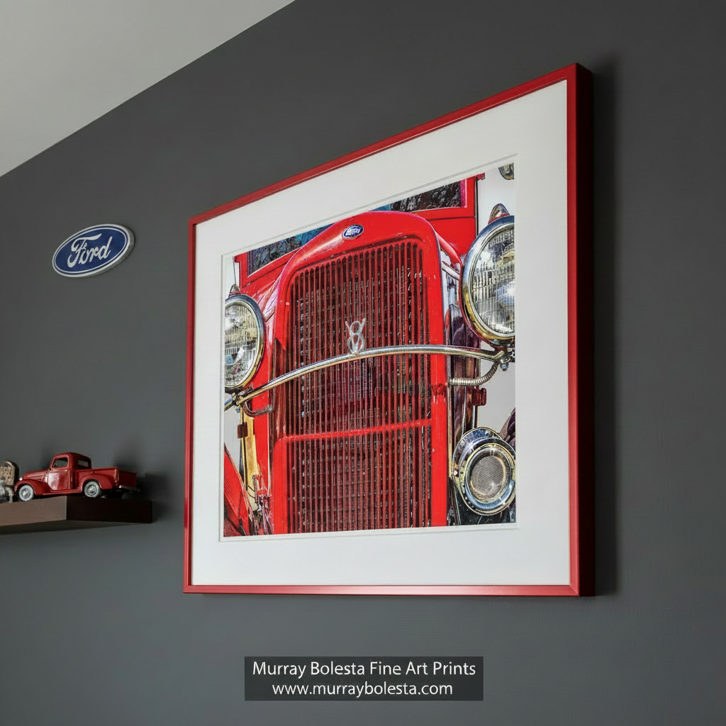 A close-up view of the front grille and headlights of a bright red vintage Ford car. Antique Ford Truck Picture as Vintage Automotive Wall Art by Murray Bolesta