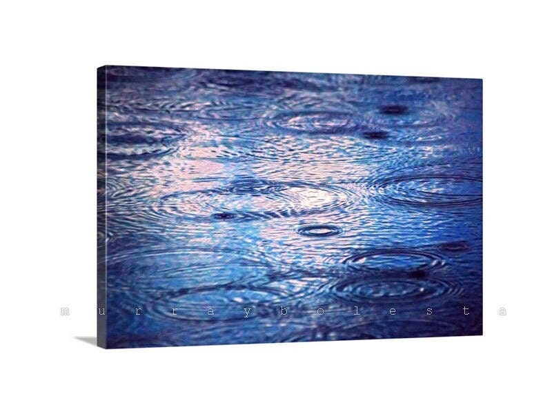 a close-up view of raindrops on a surface, creating a mesmerizing pattern of ripples and concentric circles. Indigo Raindrop Wall Art - Tucson Arizona Monsoon Storm Photography Print