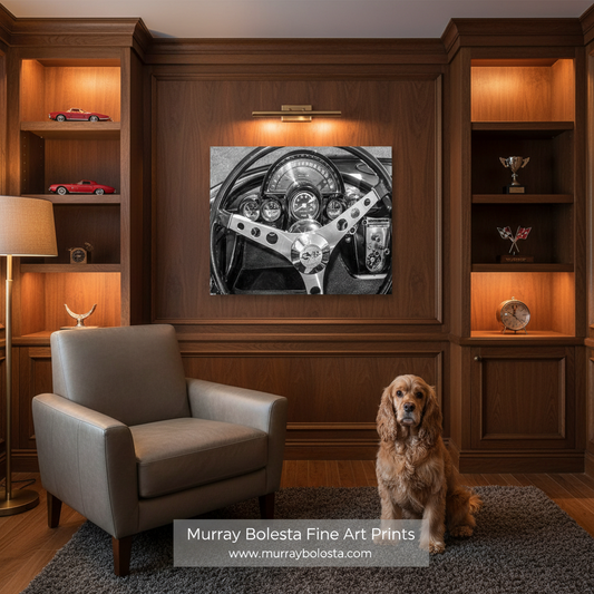 Corvette by Murray Bolesta! A black and white art print of a vintage car steering wheel mounted on a dark wood wall in a styled room with a gray armchair, a dog, and built-in shelves.