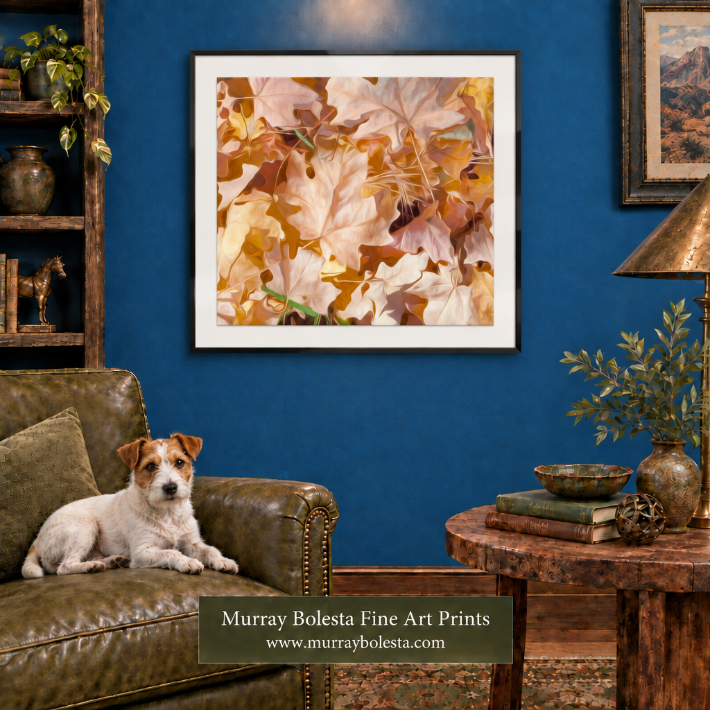 A framed art print featuring a close-up of autumn leaves in warm shades of beige, brown, and gold, displayed on a dark blue wall in a styled living room with a dog on a leather armchair and a side table nearby. By Murray Bolesta.