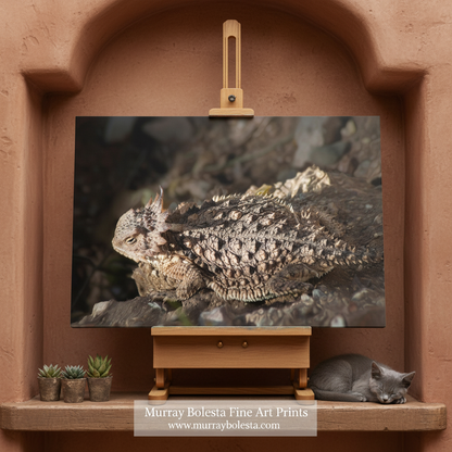 By Murray Bolesta. A framed-style art print of a horned lizard (horned toad) displayed on a small wooden easel in a terracotta-colored niche. The print depicts the textured, spiky skin of the animal in a rocky setting.