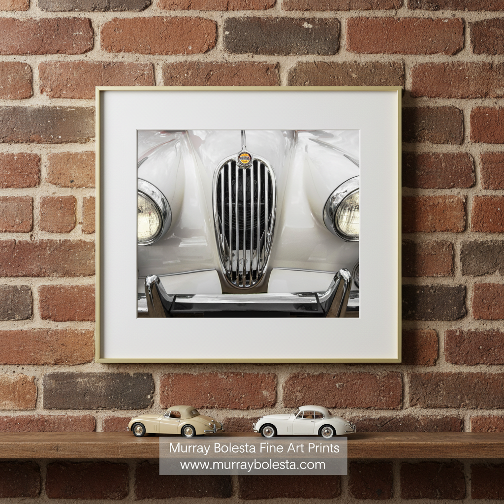 A close-up view of the front end of a classic white car, showcasing its chrome grille and headlights. Classic Jaguar XK140 Car Photograph | English Car Wall Art by Murray Bolesta