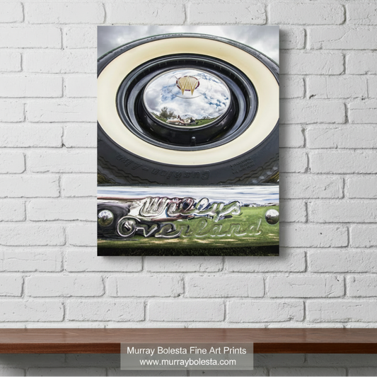 a close-up view of a vintage car's chrome bumper and round headlight, with a reflection of a kite in the center. Willys Overland Jeepster Classic Car Photography Art Print by Murray bolesta