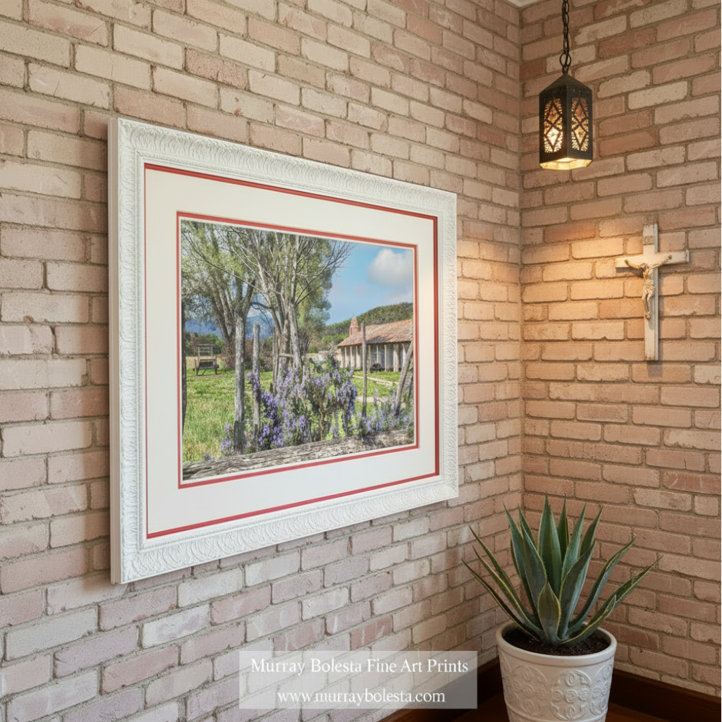 A picturesque rural scene featuring a large tree with purple flowers, a red-roofed building, and a grassy area with a wooden fence in the foreground. Purisima Spanish Mission Art - Lompoc California Wall Decor Print by Murray Bolesta