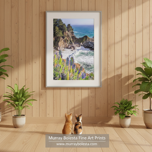 McWay Falls art by Murray Bolesta! A picturesque coastal scene with a rocky cliff overlooking the ocean, surrounded by lush vegetation and vibrant purple flowers. McWay Falls Big Sur Art Print Pacific Coast Highway California Decor
