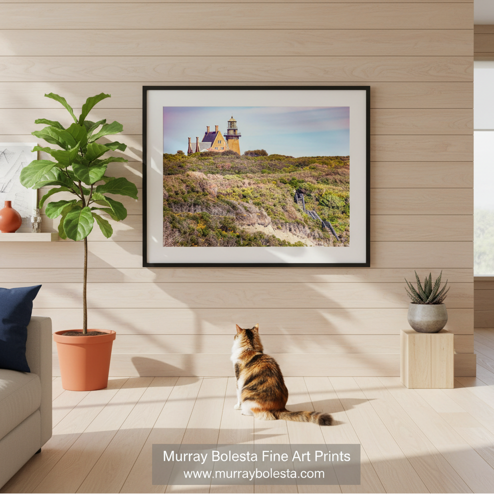 A picturesque lighthouse stands atop a hill, overlooking a lush, grassy landscape dotted with trees and shrubs. Block Island South East Lighthouse Fine Art Print | Ocean View by Murray Bolesta