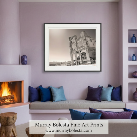 A black and white photograph of a dilapidated building with crumbling walls and columns, set against a mountainous landscape. Rhyolite Ghost Town Art - Death Valley Nevada Desert Photography by Murray Bolesta