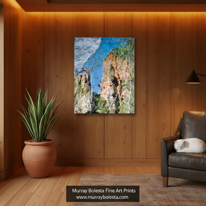 a rocky arizona canyon cliff with a mix of green and orange vegetation, set against a clear blue sky. Sycamore Canyon art by Murray Bolesta