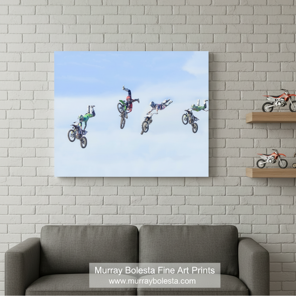 A group of people performing aerial stunts on motorcycles against a blue sky background. Motocross Art Print with Dirt Bikes in Flight | Gift for Biker by Murray Bolesta