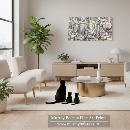 Upper East Side Manhattan by Murray Bolesta! A framed cityscape art print hangs on a light beige wall in a modern living room. The room features a light wood console, a round gold coffee table, white armchairs, and several potted plants.