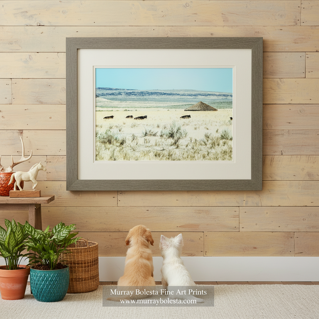 A herd of cattle grazing in a vast, arid landscape with a small, thatched-roof structure in the distance. Pete French Round Barn Art | Burns Oregon Rustic Ranch Wall Print by Murray Bolesta!