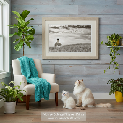 A sepia photograph of a lighthouse standing in a field of tall grass, with a cloudy sky in the background. Block Island Lighthouse with Dune Grass - Rhode Island Coastal Wall Art by Murray Bolesta!
