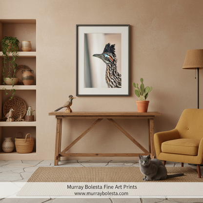 Roadrunner bird by Murray Bolesta. A framed art print of a bird of prey is displayed on a beige wall above a wooden console table in a styled living room setting with a yellow armchair, potted plant, and a gray cat on the floor.