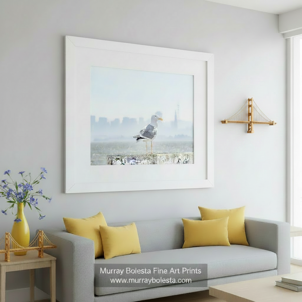 A seagull stands on a concrete ledge, overlooking a cityscape with buildings and a tower in the distance.San Francisco Bay Seagull - Sutro Tower Coastal Bird Wall Art by Murray Bolesta