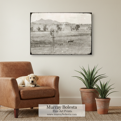 A black and white photograph depicting a rural landscape with a windmill, trees, and horses grazing in the foreground. Santa Rita Mountains Ranch Landscape | Vintage Equestrian Art by Murray Bolesta!