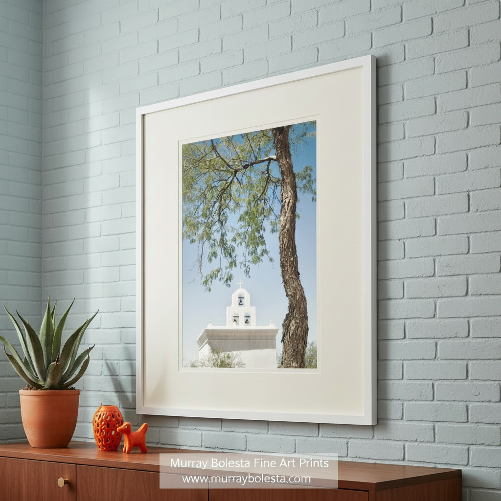 a white bell tower with a cross on top, surrounded by a tree with green leaves and branches. San Xavier Mission Chapel Art - Tucson Arizona Desert Wall Print by Murray Bolesta