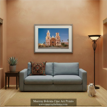 A framed art print of a Spanish-style church in Tucson Arizona displayed on a textured terracotta wall above a light blue sofa in a modern living room setting. The print is from Murray Bolesta Fine Art Prints, as indicated by the text overlay at the bottom.