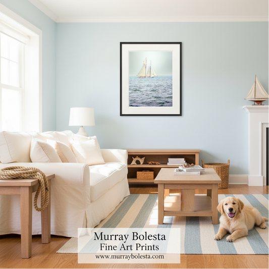 A framed art print of a sailboat on blue ocean waves displayed on a light blue wall in a bright, modern living room with a white sofa and a golden retriever dog.