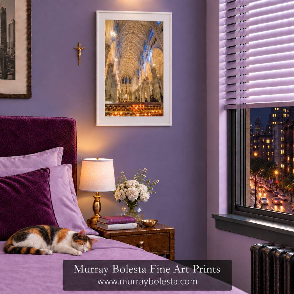 A framed art print of a cathedral interior with warm candlelight hangs on a lavender bedroom wall above a bed with purple bedding and a sleeping cat. The print is shown in a styled room setting with window blinds, a nightstand, and a visible watermark for St patrick's cathedral art by Murray Bolesta Fine Art Prints.