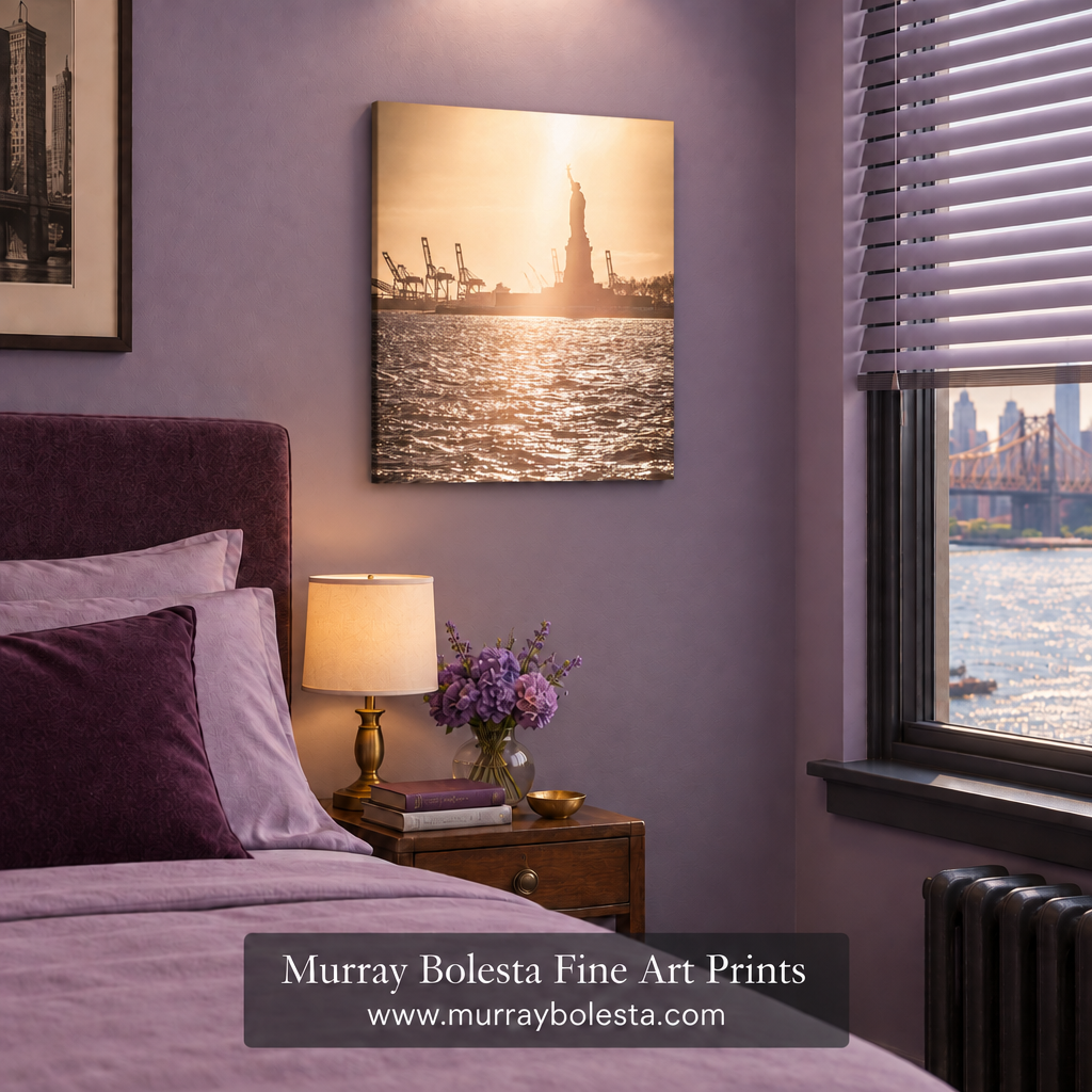 A square canvas art print of the Statue of Liberty and harbor at sunset, displayed on a lavender wall in a styled bedroom setting. The print features warm golden-hour lighting reflecting off the water, with the Statue of Liberty centered against a dark silhouette. By Murray Bolesta.