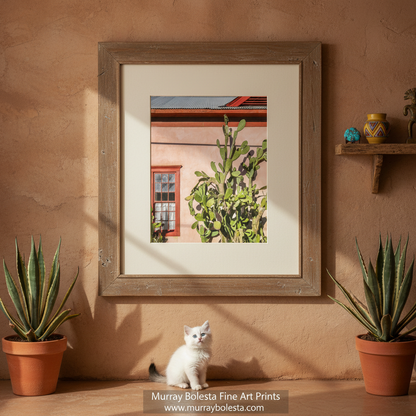 A framed art print featuring a vibrant image of a building with a large cactus in front, set against a pink wall with a window and red trim. Tucson Old Pueblo art by Murray Bolesta!