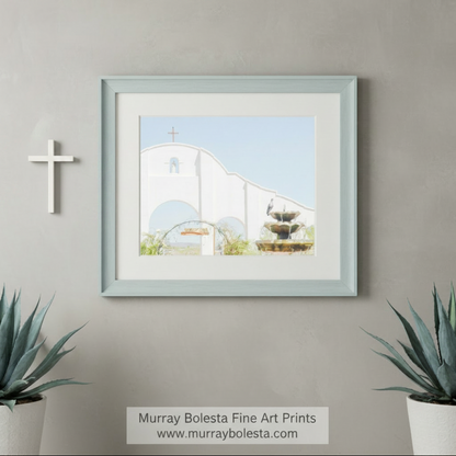 a white church with a cross on top, surrounded by a fountain and a bird perched on a nearby structure. San Xavier Southwest Mission Architecture Art - Tucson AZ Print by Murray Bolesta