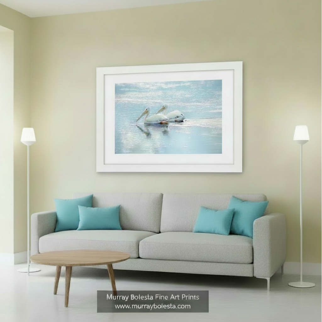 Two white pelicans with yellow beaks are resting on the water's surface, their reflections visible in the calm water. White Pelican Bird Art - Dreamy Wetlands Wildlife Decor Print by Murray Bolesta
