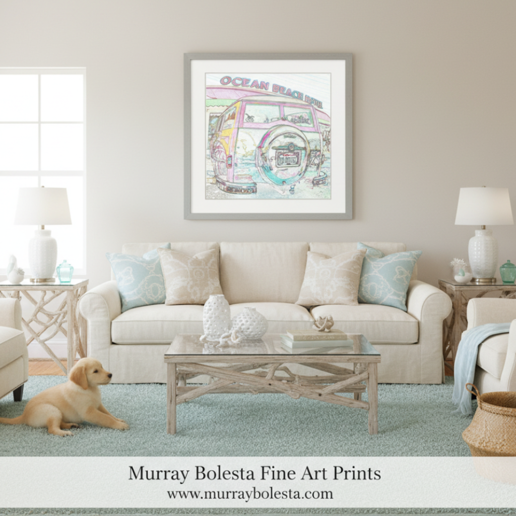 A framed art print featuring a colorful retro beach bus illustration with the words 'Ocean Beach' hangs on a beige wall above a cream sofa in a styled living room. A small golden puppy is lying on a light blue rug at the bottom left.